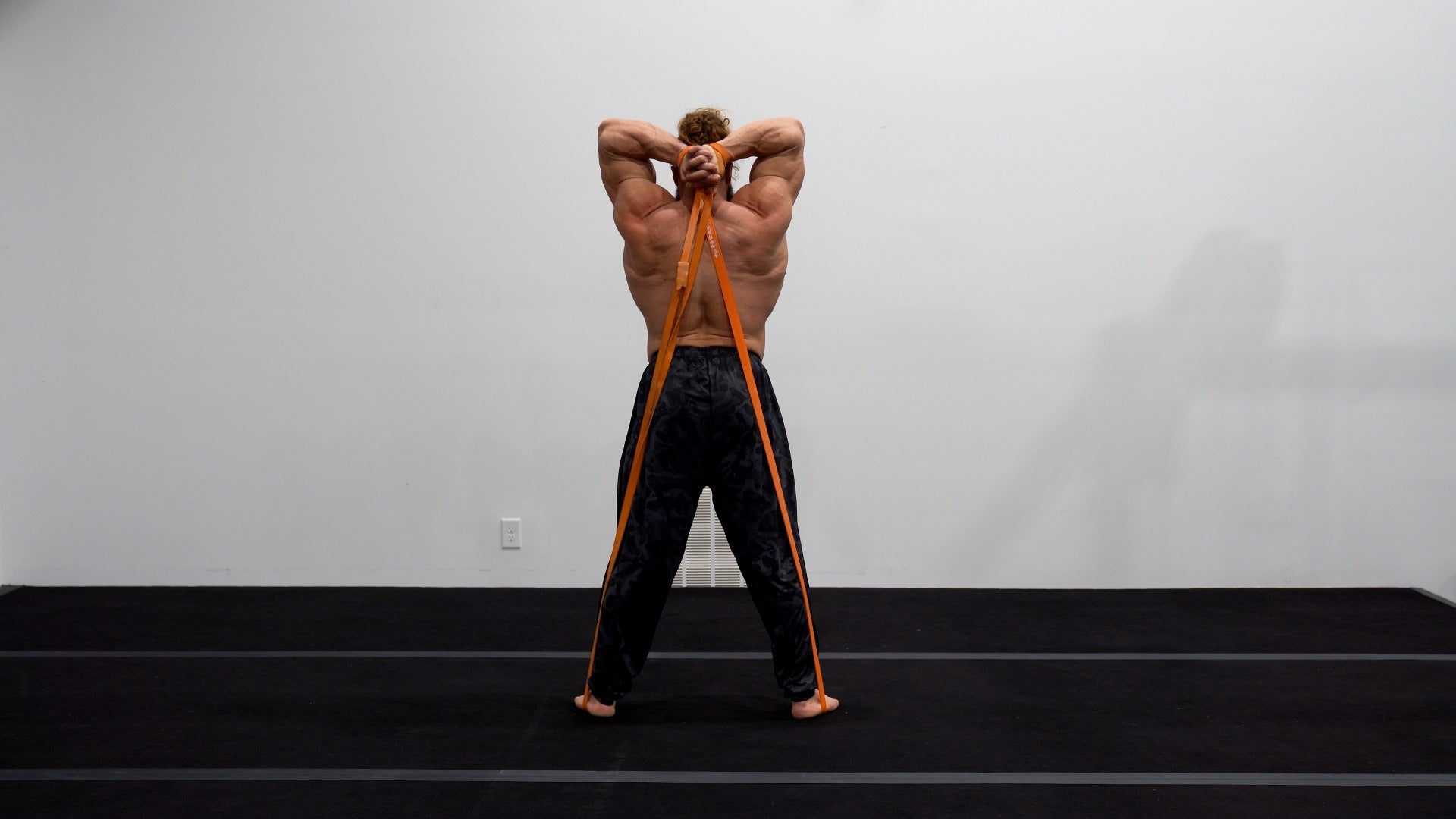 Man using resistance bands for back exercise against a plain background