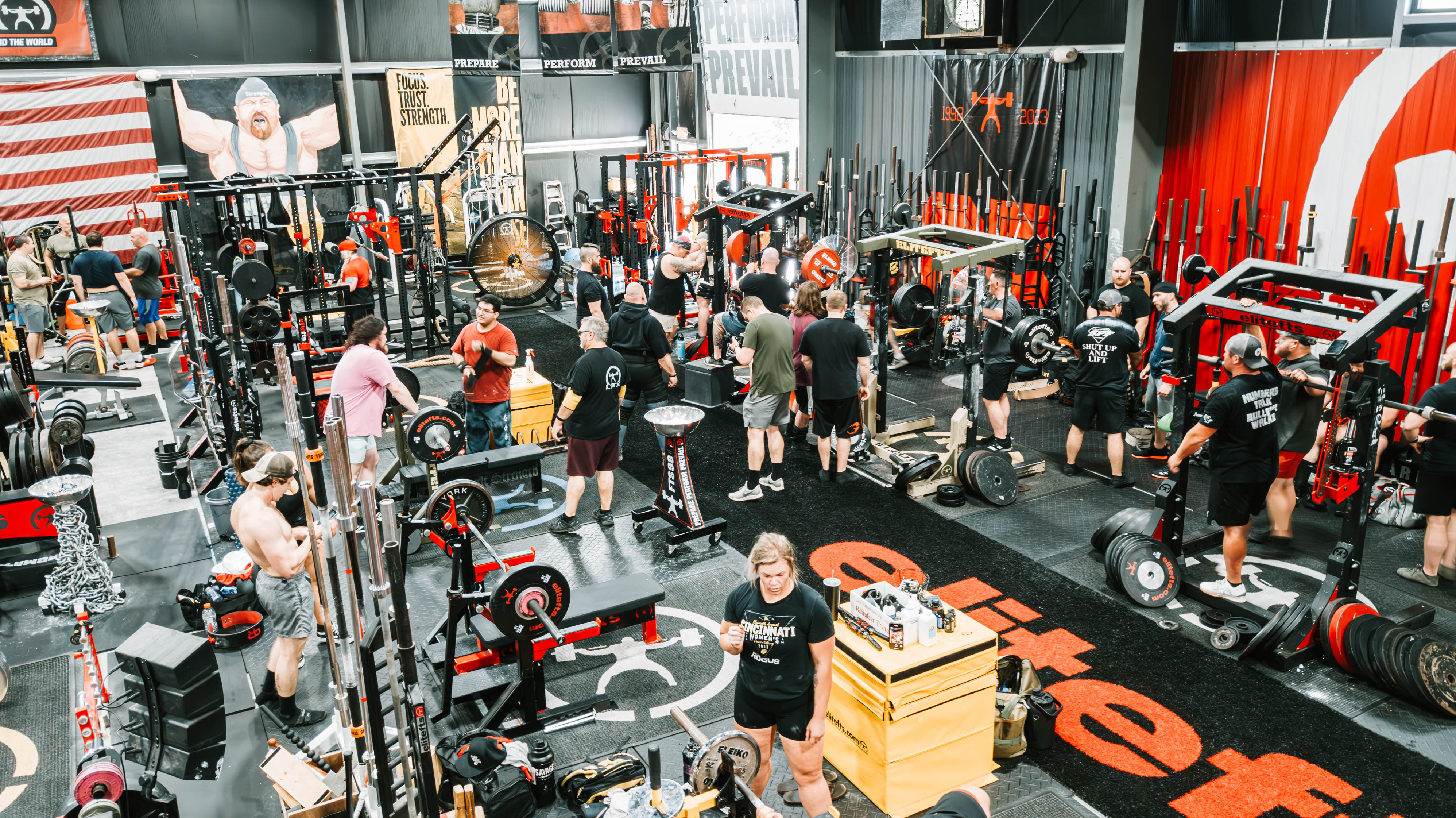 Gym interior with various exercise equipment and people working out.