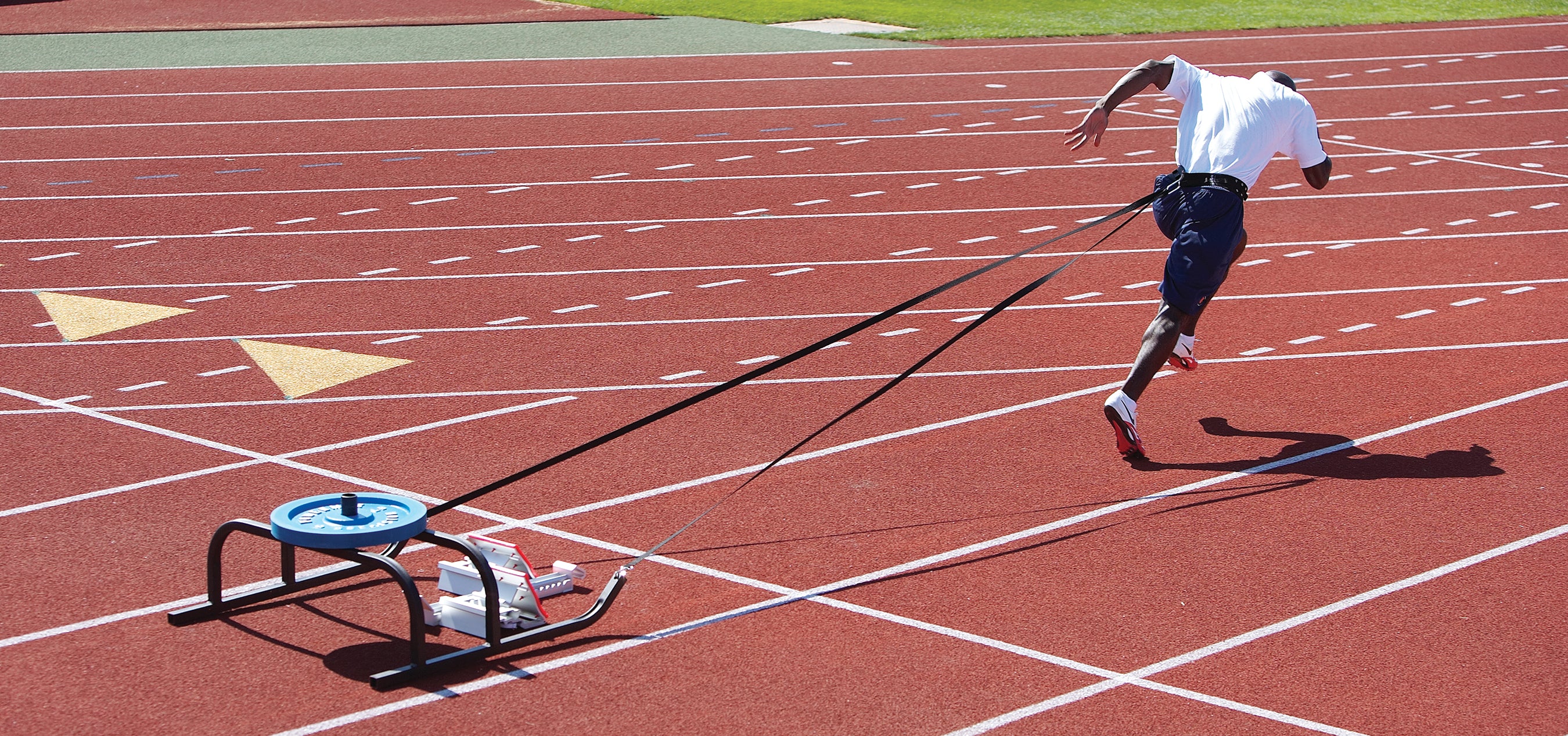 Person running on a track with a starting block and strap